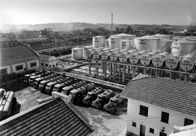 Flota de camiones cisterna junto a tanques horizontales y verticales. (Propiedad: CLH, Archivo Histórico de CAMPSA)
